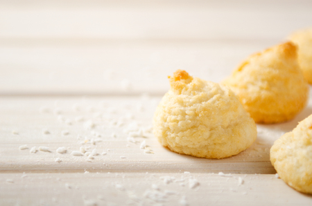 Coconut biscuits sprinkled with coconut chips on a wooden white table.の写真素材