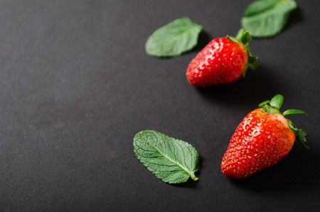 Strawberries and mint. Red ripe berry with mint leaves on a black background. Copy space.の写真素材