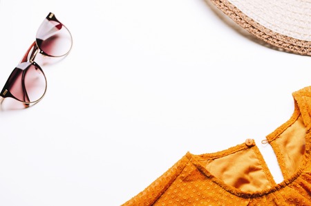 Orange dress, straw hat and glasses on a white background. Fashionable concept of summer vacation,...