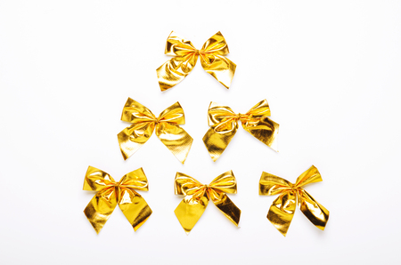 Golden bows on a white background in the form of Christmas tree. Concept, new year. Top view, flat lay.の写真素材