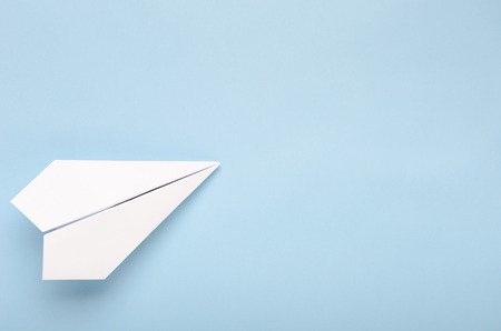 Paper plane on a blue background. Concept of flight, travel, transfer. Top view, copy space, flat layの写真素材