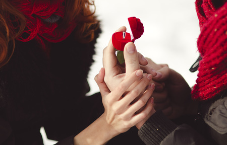 A man in love proposal to marry him to his woman outdoor. Winter romance, ring as giftの写真素材
