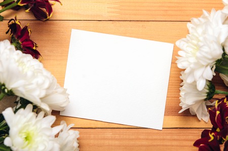 Frame of white and red chrysanthemum flowers on craft paper. Card for congratulations, inscriptions, template, mock up. Wooden background, copy space, top view, flat layの写真素材