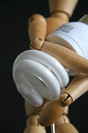 Wooden maniqan holding power saving light bulbの写真素材
