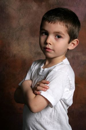 Boy with his arms folded on brown background - closeup