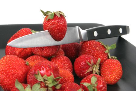 strawberries on Black Plate over White with knifeの写真素材