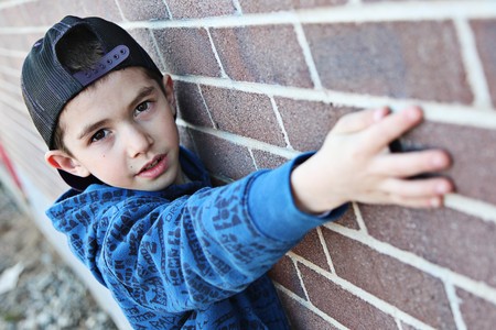 Young child hanging out near a grungy wall の写真素材