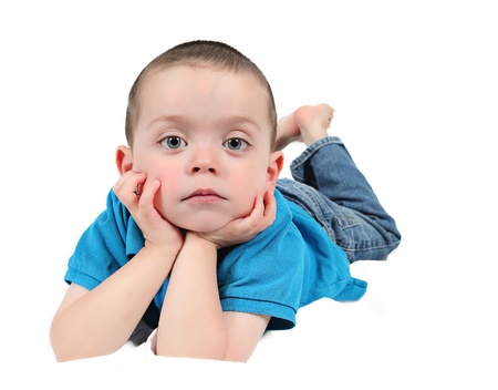 Cute little boy with hands under chin on white backgroundの写真素材