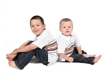 Brothers sitting together back to back on whiteの写真素材
