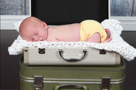 Cute baby sleeping in suitcare bedの写真素材