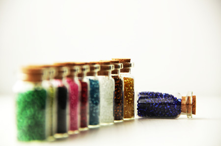 Tiny glass bottles filled with beads of different colorsの写真素材