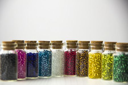 Tiny glass bottles filled with beads of different colorsの写真素材