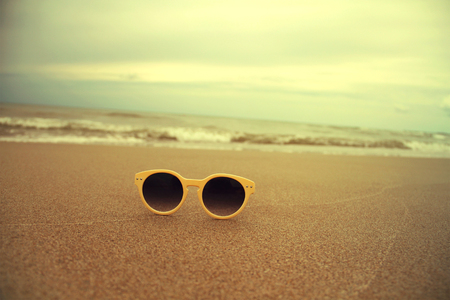 Sunglasses on the sand on beach beautiful summer photo in vintage styleの写真素材