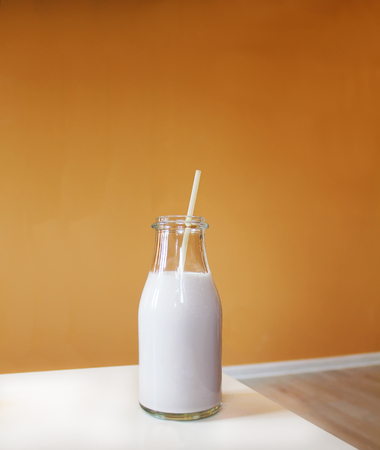 Milkshake with straw on white table and orange backgroundの写真素材