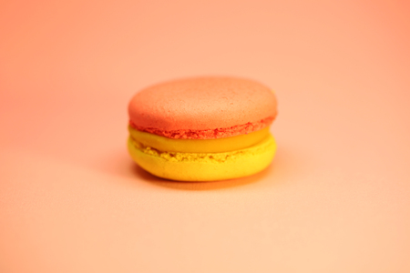 Yellow and red macaroon cake on pink background bright food photographyの写真素材