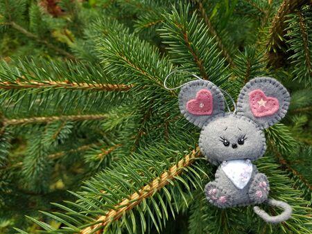 Christmas felt decoration on a spruce branch. Handmade bauble figurines symbol of the year - rat. Holiday background with a copy space.の写真素材