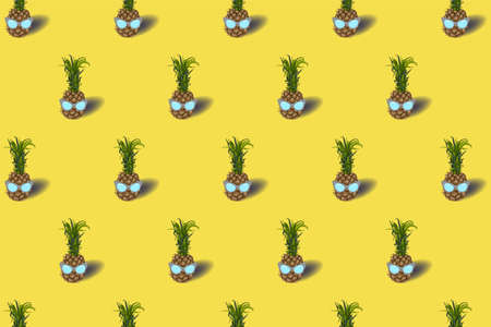 Pattern with pineapple fruit in a sunglasses - on an pastel yellow background. Ultimate grey colored glasses. Summer concept - stylish vacation, juicy exotic and tropical fruit. Bright stock vector illustrationのイラスト素材
