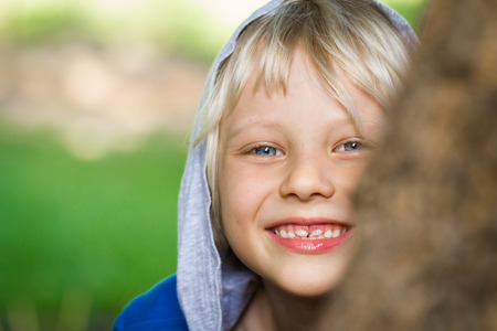 Happy child peeking from behind a tree with copy-spaceの写真素材