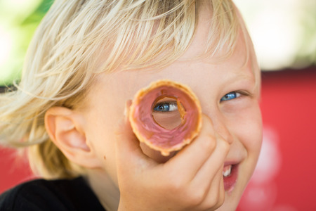 Fun portrait of a happy child peeking through his ice cream coneの写真素材