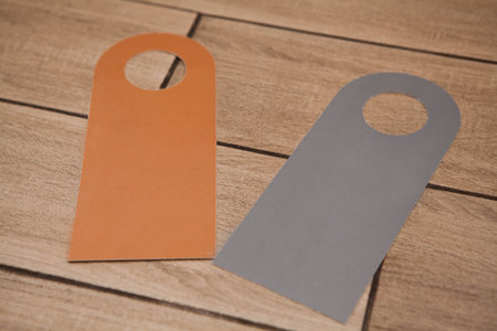 Two blank door hanger mockups in orange and gray on a wooden surface. Ideal for hotel branding, âDo Not Disturbâ or cleaning service signage design templates.の写真素材
