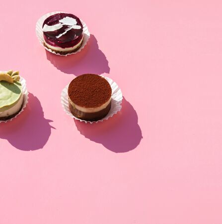 delicious and sweet cakes placed on a pink background on which the sun rays