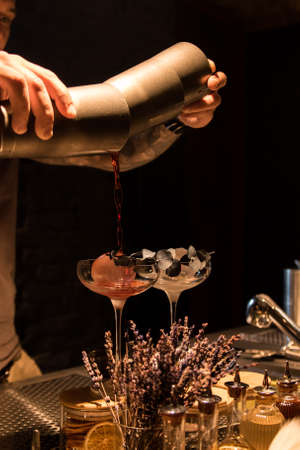 The bartender pours a cocktail into a glass in a restaurant