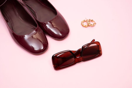 burgundy shoes, sunglasses and gold earrings on a pink backgroundの写真素材