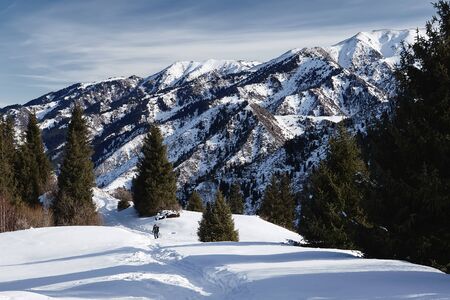 Hiker is walking on the winter trail against spectacular mountains and blue sky backgroundの写真素材