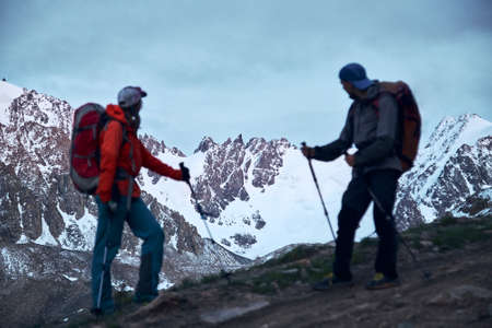 two mountain tourists looking at a glacier peaks