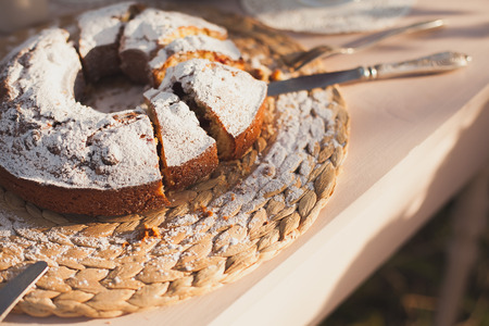 The cake strewed with icing sugar on a table. Freshly baked sweet cake. Festive breakfast. Breakfast outdoors. Festive lunch outdoors. Festive dinner outdoors.Freshly baked sweet cake closeup . Baking on a table. Summer dinner outdoors.の写真素材