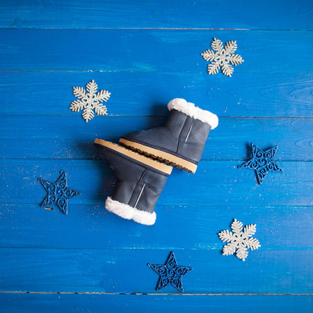 winter children's clothing, fur boots on a blue wooden background.の写真素材
