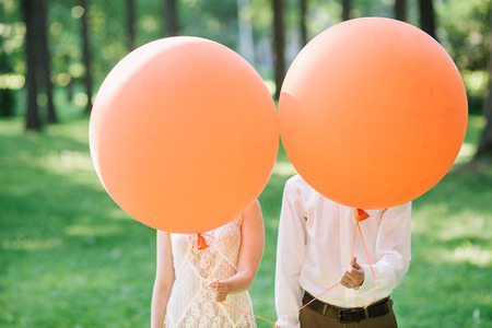 newlyweds with orange balloons. the amusing photo with newlyweds.の写真素材
