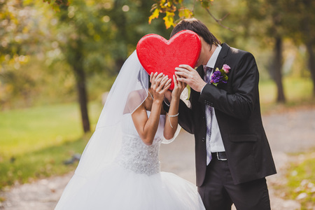 Happy wedding couple holds big red heart in hands.の写真素材