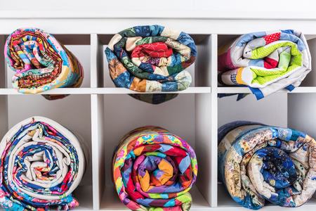 color blankets in style a patchwork put in a roll lie in different cells of a box on a white background. Colorful quilt.の写真素材