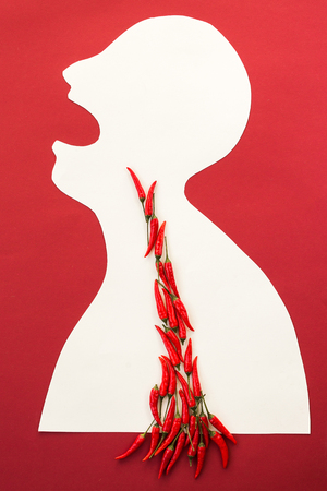 concept of human disease, suffering and stinging pain - abstract white male man isolated on red background scream with open mouth from pain in stomach, burning pain such as spicy chili peppersの写真素材