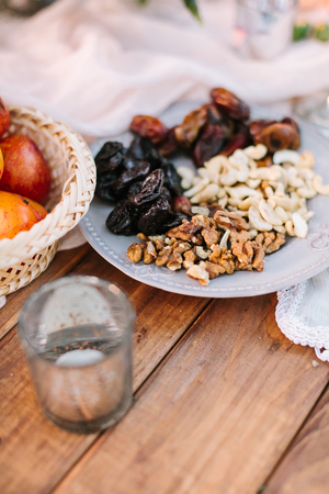 picnic, food, summer, holiday concept - close up on the festively decorated table with beautiful fresh and dried fruits, nectarines, walnuts, cashews, dates, prunes, tablewareの写真素材