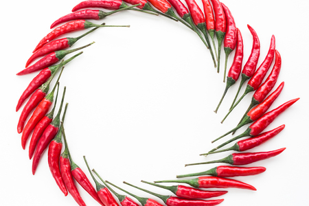 red hot chili peppers, popular spices concept - decorative pattern of circle from hot chili peppers on white background, beautiful hot figure of lying pepper, top view, flat lay, free space for textの写真素材