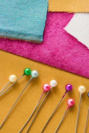 needlework, quilting, sewing and tailoring concept - beautiful purple, blue, white and mustard color patches with a lot of cute pins, macro, flat lay, top view, verticalの写真素材