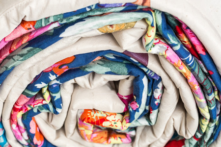 patchwork, sewing and fashion concept - macro of beautiful colorful quilted blanket is rolled up in a tube at studio, warehouse of finished products, side viewの写真素材
