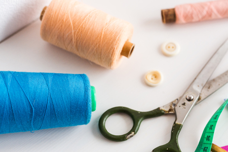 sewing tools, patchwork, tailoring and fashion concept - close-up on white desk in studio, colorful...