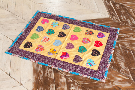 Color Patchwork quilt on a wooden background. Part of patchwork quilt as background. Handmade.