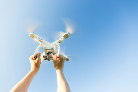 quadcopter outdoors, aerial imagery and recreation concept - closeup on human hands grip on frame of...