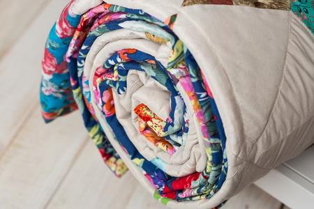 patchwork, sewing and fashion concept - close-up on cute colorful quilted blanket at white shelves with storage compartment in studio, white floor in a warehouse of finished products, side viewの写真素材