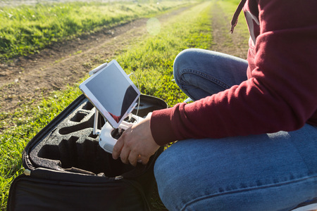 quadcopter flights outdoors, aerial imagery and tech hobby, recreation concept - quadrocopter flight preparation, installation of the tablet PC in holder of drone remote control by male handsの写真素材
