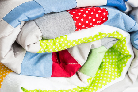 sewing, patchwork and fashion concept - close-up on bright beautiful multi-colored quilt, folded...