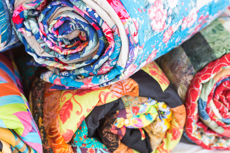 relaxation, coiziness, rest concept. stack from four different rags rolled up into tube has various colors. Top one is blue and decorated by images of flowers and petalsの写真素材