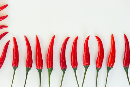 red hot chili peppers, popular spices concept - vertically stacked row of pods of the red hot chili peppers on a white background, top view, flat lay, free space for your textの写真素材