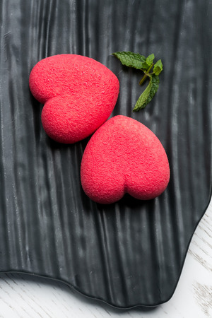 close-up of beautifully decorated delicious red heart shaped strowberry dessert on a black stone plate. concept of sweet pastry and tuck.の写真素材