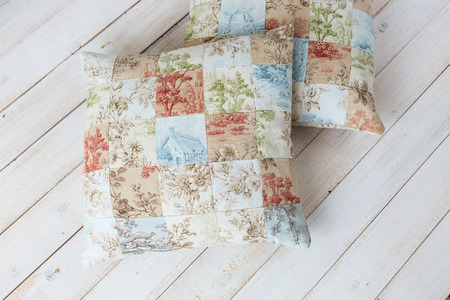 warmness, art, ornament concept. pare of realy soft cushions inside pillowslips made in patchwork style with spellbinding pattern stitched from varied pieces of satin textileの写真素材