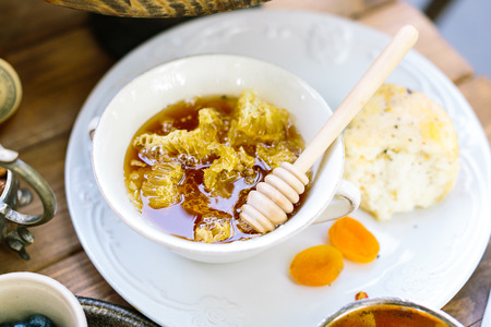 confection, dinner, meal concept. the finger bowl fullied of sunny yellow honey and honeycombs till...